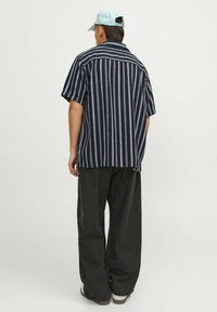 Koszulka w marynarskie paski z krótkim rękawem, wykonana z lekkiego materiału; posiada prosty dół i nieco luźny krój. Noszona z ciemnymi spodniami.