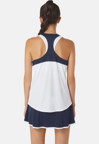 Sportieve racerback tanktop in marineblauw en wit, met een afgeronde zoom en een uitlopende rok met een gelaagd ontwerp aan de onderkant.