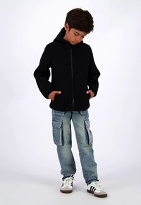 Mustast lukuga lukustatav kapuutsiga dressipluus kõrge kraega, küljetaskutega; kombineeritud helesiniste cargo teksade ja valgete tossudega, millel on mustad triibud.