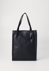 Sac fourre-tout en cuir noir avec un design vertical, des poignées plates et un logo embossé à l'avant. Texture lisse, style minimaliste.