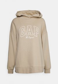 Beżowa bluza z kapturem z dużym białym logo "GAP" z przodu, miękki materiał bawełniany, długie rękawy i kaptur ze sznurkiem.