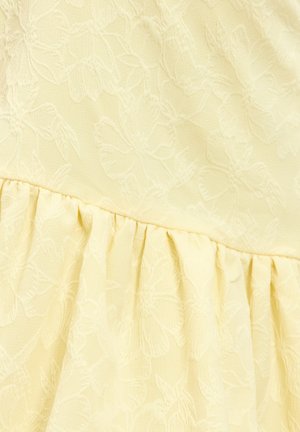 Geel stof met bloemenpatroon en zachte textuur, met een geplooid ruchesdetail aan de onderkant. Het geperste bloemenontwerp geeft diepte.