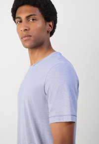 Tricou cu maneci scurte, în dungi, de culoare albastru deschis și alb. Fabricat din bumbac, cu guler rotund și detalii de cusătură vizibile.
