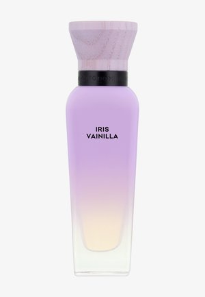 Flacon de parfum en verre haut avec un dégradé du lavande au beige pâle, avec un large bouchon en bois clair et une bande noire, étiqueté "Iris Vainilla".
