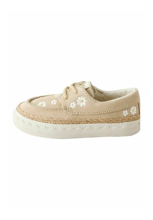 Beige suède casual schoen met witte madeliefjesborduursel, veterluiting aan de voorkant, gevlochten rand boven dikke witte rubberen zool.