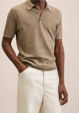 Koszulka polo z krótkim rękawem z beżowego, teksturowanego materiału z kołnierzykiem, zestawiona z jasnymi, prostymi spodniami.
