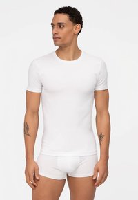 Maglietta bianca a maniche corte realizzata in morbido cotone, abbinata a boxer bianchi. Entrambi gli indumenti presentano un design semplice e senza cuciture.