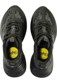 Fekete tornacipő sima bőr felsőrésszel és szegecselt részletekkel. Lekerekített orr, mintás talp és élénk sárga insole logó.