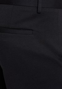 Dunkel schwarze Hose aus strukturiertem Stoff, mit einer dezenten seitlichen Tasche und einem glatten Bund. Maßgeschneiderte Passform mit einem klaren Design.