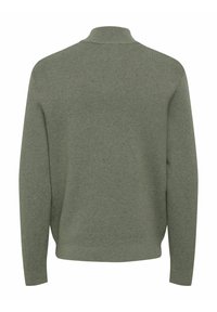 Zielony sweter z dzianiny z wysokim kołnierzem, prążkowaną fakturą i bocznymi rozcięciami. Posiada długie rękawy i luźny krój.