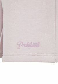Lys rosa genserstoff med ribbet tekstur, med brodert "Forbudt"-logo i matchende rosa på kanten.