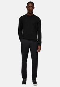 Black sweater with long sleeves, round neckline; paired with black trousers and black sneakers. Smooth texture, fitted design.