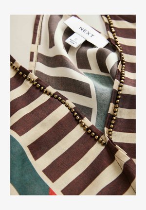 Blusa stampata con strisce orizzontali marroni e crema con accenti turchesi. Decorata con perline di bronzo circolari lungo il colletto.