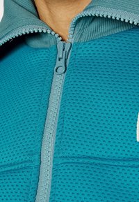 Teal fleecetröja med dragkedja och strukturerad tyg samt släta detaljer; har en matchande dragkedja och huva med ribbade kanter.