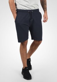 Shorts de sport bleu marine foncé en tissu léger, dotés de poches latérales et d'une taille élastique avec cordon de serrage pour un ajustement optimal.