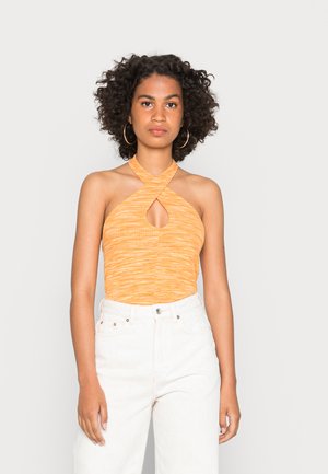 Top de halter em tecido laranja canelado com um detalhe em forma de buraco, combinado com calças brancas de cintura alta. A textura parece suave e elástica.