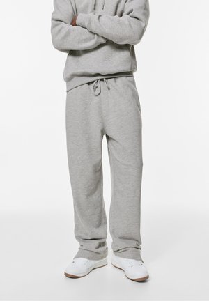 Grå sweatpants av mjukt tyg med elastisk midja och snörning. I kombination med vita sneakers. Enkel design, avslappnad passform.