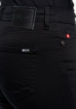 Zwarte denim jeans met een leren label en een klein merklabel. Ontworpen met standaardzakken en subtiele stikdetails.