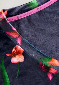 Tume lillemustriga topp, millel on pehme, sametine tekstuur ning roosad ja rohelised aktsendid. Sildil on kiri "b by Ted Baker". V-kaeluse disain.