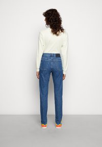 Ljusblå denimjeans med rak passform, hög midja, två bakfickor och en logotyppatch vid midjebandet.