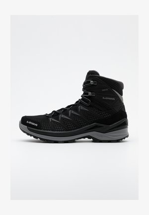 Schwarze Wanderstiefel mit einem Obermaterial aus Mesh und Wildleder, Gore-Tex-Futter, verstärkter Zehenpartie und robustem Profilsohle für besseren Halt. Verfügt über verstellbare Schnürsenkel.
