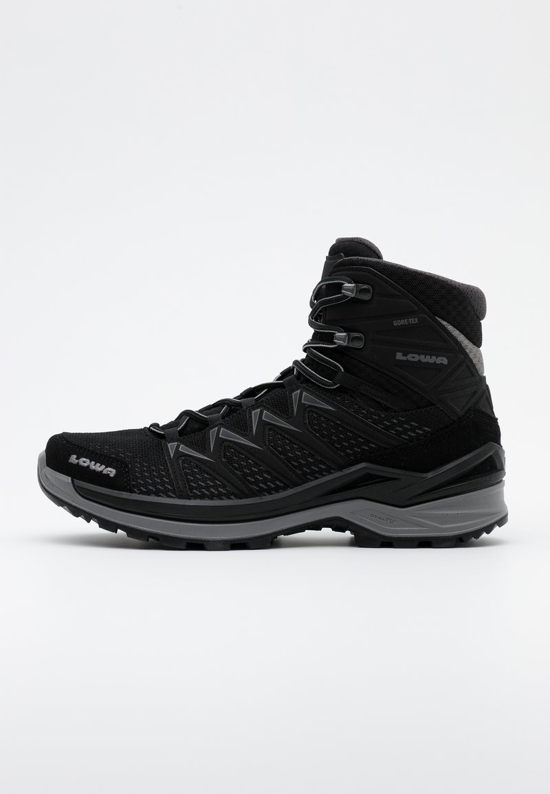 Bota de senderismo negra con parte superior de malla y ante, forro Gore-Tex, puntera reforzada y suela robusta para tracción. Cuenta con cordones ajustables.
