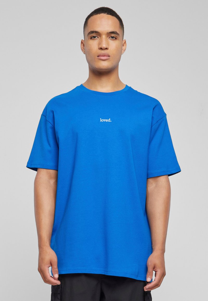 Blå bomull T-skjorte med korte ermer, med en rund hals og ordet "loved." i hvit tekst på brystet. Figursydd design.