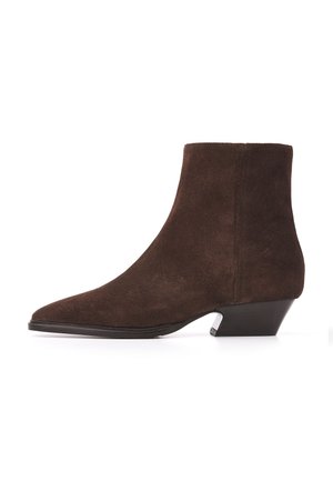 Brun ruskind ankleboot med lav, vinklet hæl og spids tå vist i profil mod hvid baggrund.