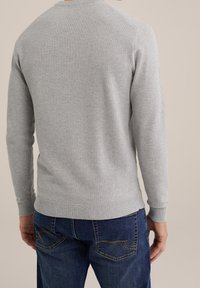 Gray knitted sweater with a textured finish, featuring a ribbed neckline and cuffs, paired with blue denim jeans, showing back view.