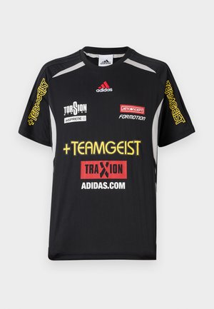 Musta urheilupaita, jossa on lyhyet hihat, keltainen ja punainen logo sekä grafiikka, mukaan lukien Adidas-merkkiviittaukset ja useita sponsorilogoja.