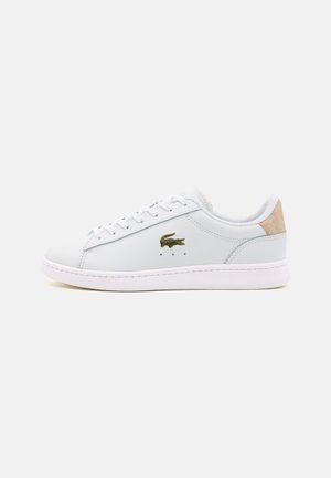 Baskets blanches en cuir avec un bout rond, semelle blanche, lacets plats, logo vert sur le côté et accent texturé beige sur le talon.