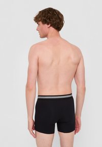 Svarta boxershorts med svart midjeband som har grå ränder. Mjuk, elastisk tyg som formar sig efter kroppens konturer.