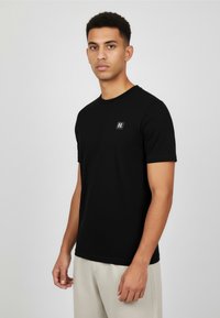 Czarny, krótki rękaw t-shirt wykonany z miękkiego materia�łu, z małą naszywką z logo na piersi i okrągłym dekoltem.