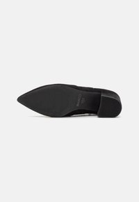 Black suede pointed-toe pump with a textured upper, smooth sole, and low heel. The sole features subtle branding on the underside.