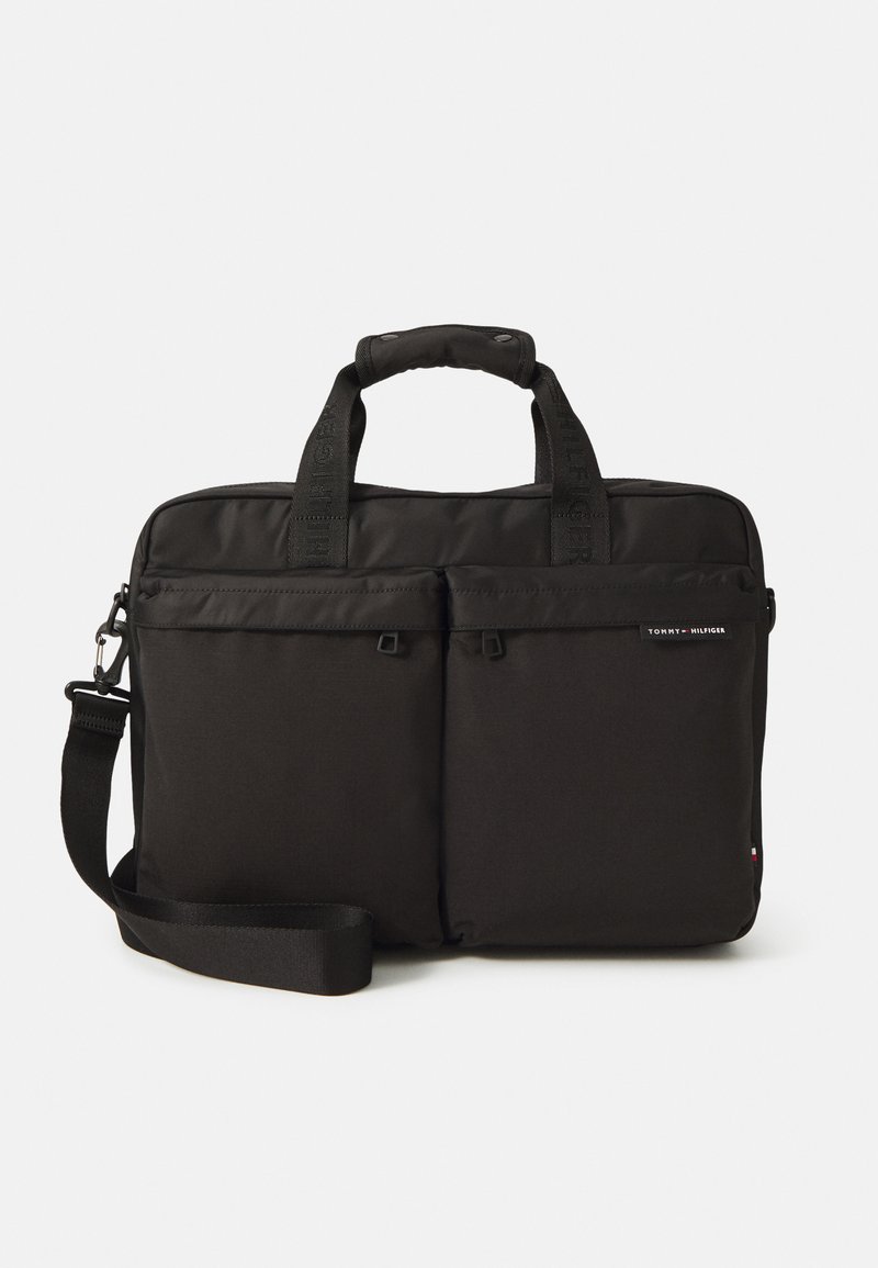 Sort laptoptaske lavet af stof med to frontlommer, dobbelt håndtag og justerbar skulderrem. Udstyret med logo-detaljer.