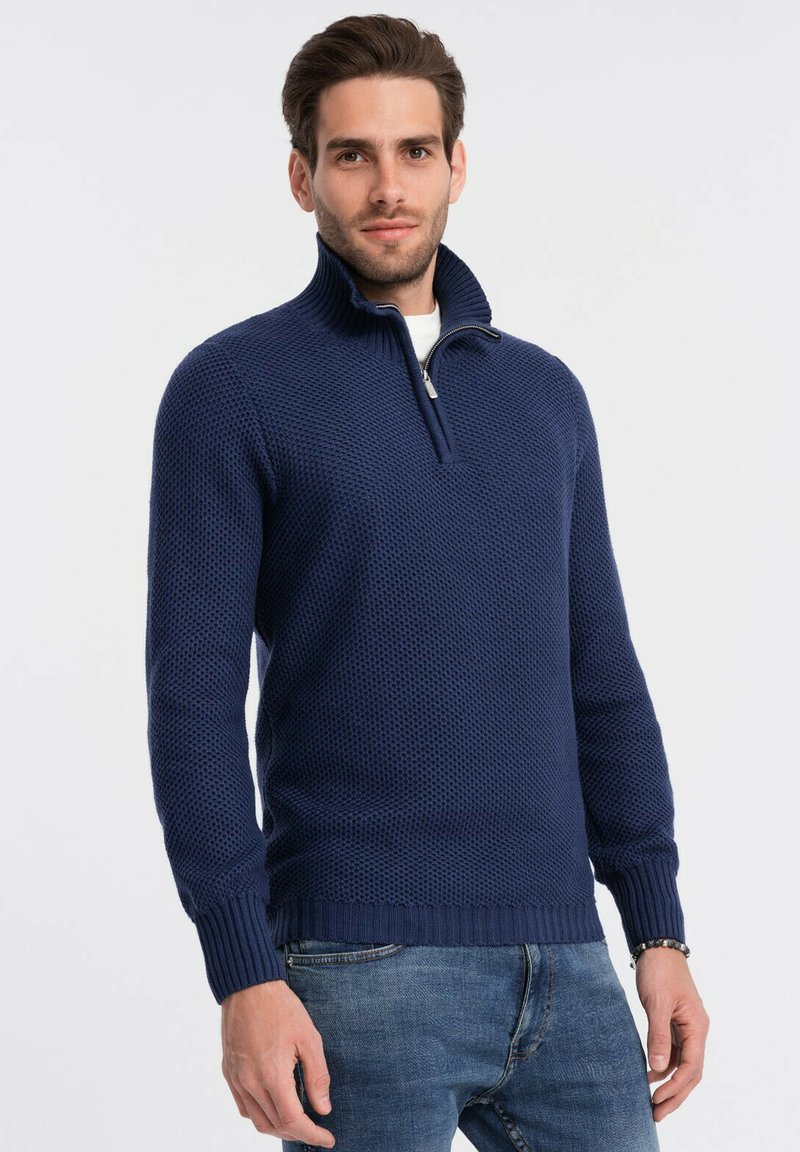 Granatowy sweter z dzianiny z wysokim kołnierzem, z ćwierć zamkiem, prążkowanymi mankietami oraz teksturowanym wzorem na całej powierzchni materiału.