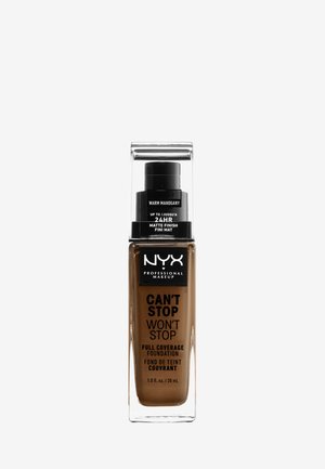 Bouteille de fond de teint avec un corps rectangulaire clair et un couvercle à pompe noir. Le texte de l'étiquette comprend "Can't Stop Won't Stop", la couleur "Warm Mahogany", et une finition mate de 24 heures.
