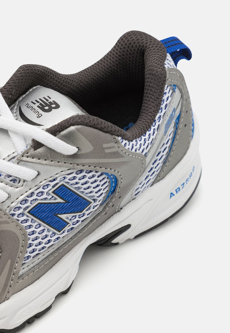 Zapatilla de running gris y azul con parte superior de malla, acentos texturizados, cordones blancos y suela negra. Logotipo "N" mostrado de manera prominente.