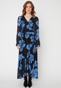Dlhé čierne šaty s modrým kvetinovým vzorom, s velmičkovým dizajnom, dlhými rukávmi a vrstvenými volánmi na leme. Elegantná, priesvitná látka.