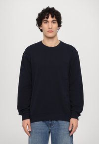 Sweatshirt azul-marinho com mangas longas, decote redondo e pormenores texturizados na parte da frente. Material suave e corte descontraído.