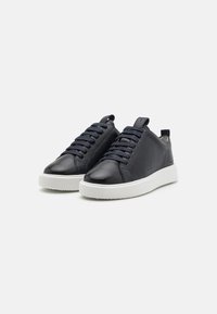 Marine lærersneakers med teksturfinish, hvit gummisåle og flettede lisser. Har en pull-tab på hælen for enkel påkledning.
