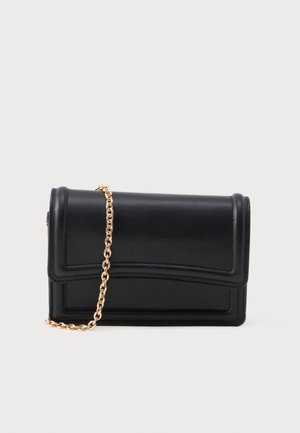 Bolso cruzado rectangular de cuero negro con tapa curva y correa de cadena dorada sobre un fondo claro.