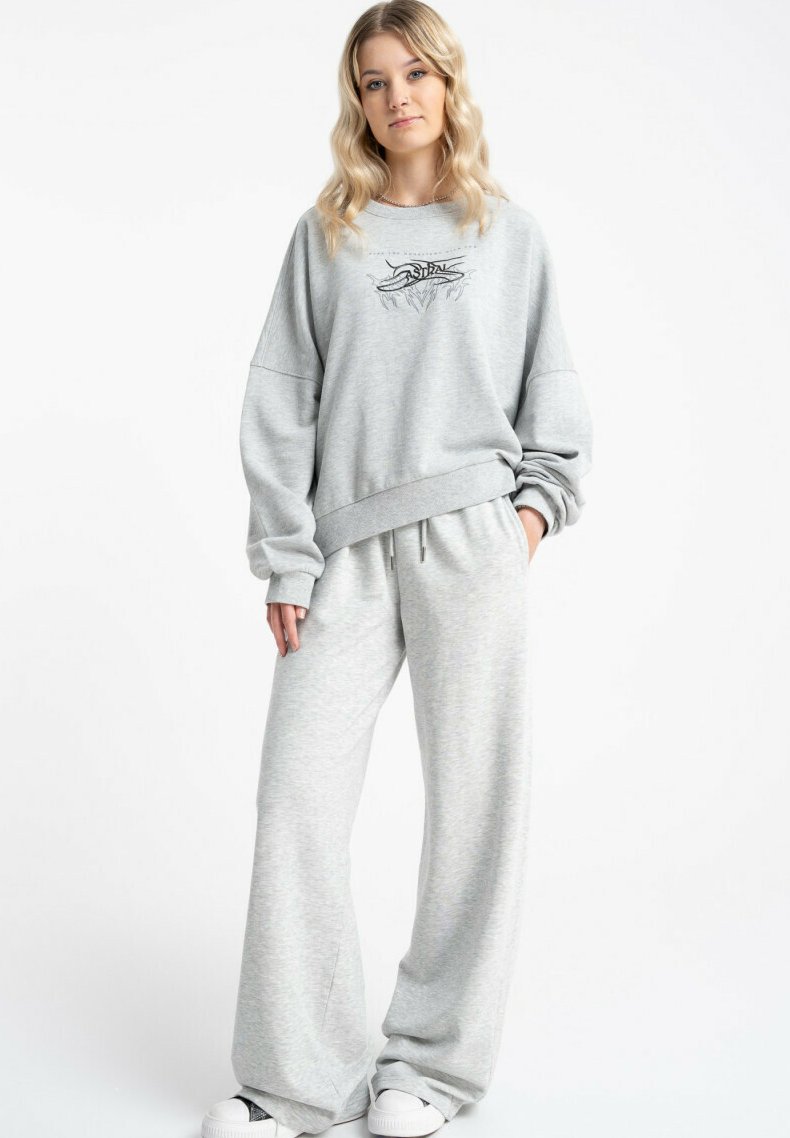 Jasnoszara bluza z oversize'owymi rękawami i grafiką na przodzie, zestawiona z dopasowanymi szerokimi spodniami dresowymi z miękkiego materiału.