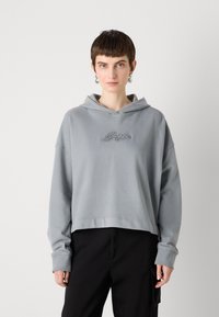 Grå kort hoodie med en kenguru-lomme foran og brodert logo. Har en hette med snor og ribbede mansjetter, laget av myk stoff.