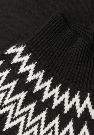 Suéter negro de punto con un alto cuello acanalado y un patrón de zigzag blanco en la parte frontal, con un acabado de textura suave.