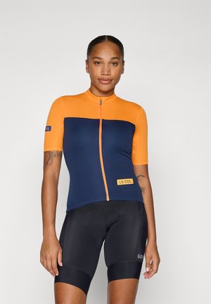 Short-sleeve cycling jersey in orange and navy, featuring a front zipper, LE COL logo, and a sleek, athletic fit. Worn with black shorts.