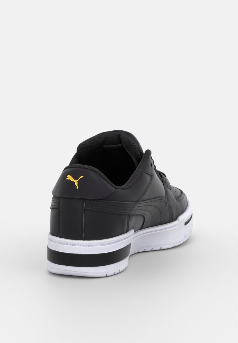 Baskets en cuir noir avec un col de cheville rembourré, une semelle intermédiaire blanche et une semelle extérieure noire. Présente un logo Puma jaune sur le talon.