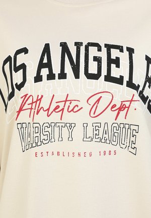 Beżowy sweatshirt z wyraźnym czarnym i czerwonym napisem: "LOS ANGELES," "Athletic Dept.," "VARSITY LEAGUE," oraz "ESTABLISHED 1985." Miękka faktura.