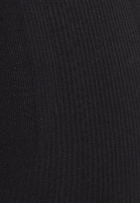 Černá pletená látka s ribbovým vzorem, která má těsně rozmístěné svislé pruhy. Materiál se zdá být měkký a elastický.