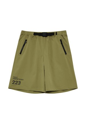 Osoba nosząca oliwkowo zielone szorty z czarną kieszenią na suwak i czarnym nadrukiem "HALO 223" na lewym udzie, w połączeniu z czarną koszulką.